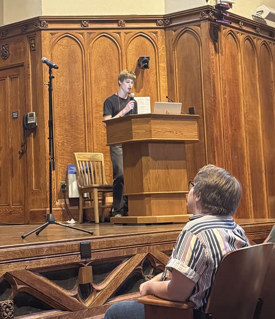 Evan Morris presenting from a podium in a wood-paneled lecture hall