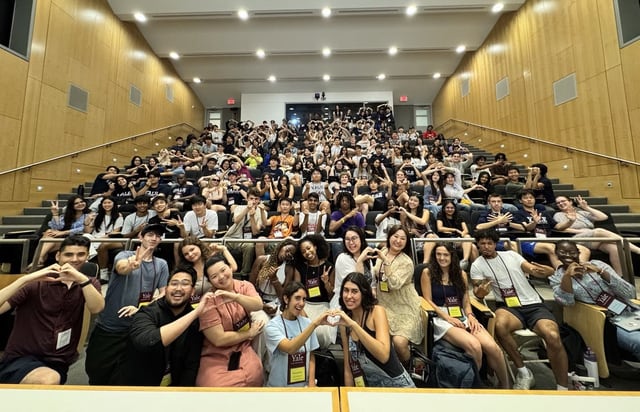 The Yale Young Global Scholars cohort filling a lecture hall, making heart and peace signs for a group photo