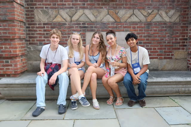 Evan Morris with four friends on a stone bench against a brick wall at Yale