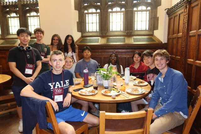 Evan Morris at a round table in a wood-paneled Yale dining hall with his Yale Young Global Scholars group