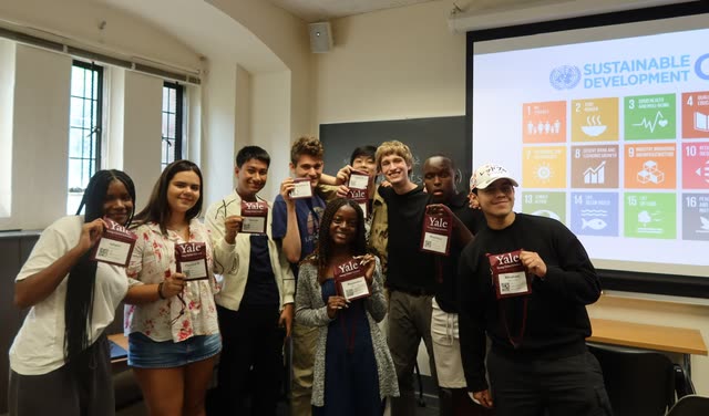 Evan Morris with classmates at Yale Young Global Scholars, holding up their program badges in front of a slide of the UN Sustainable Development Goals
