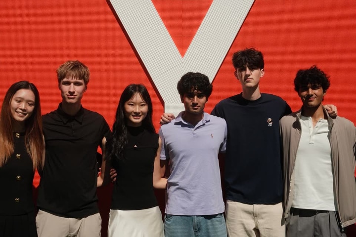 Evan Morris, second from left, with five other students in front of a large white Y on a red wall